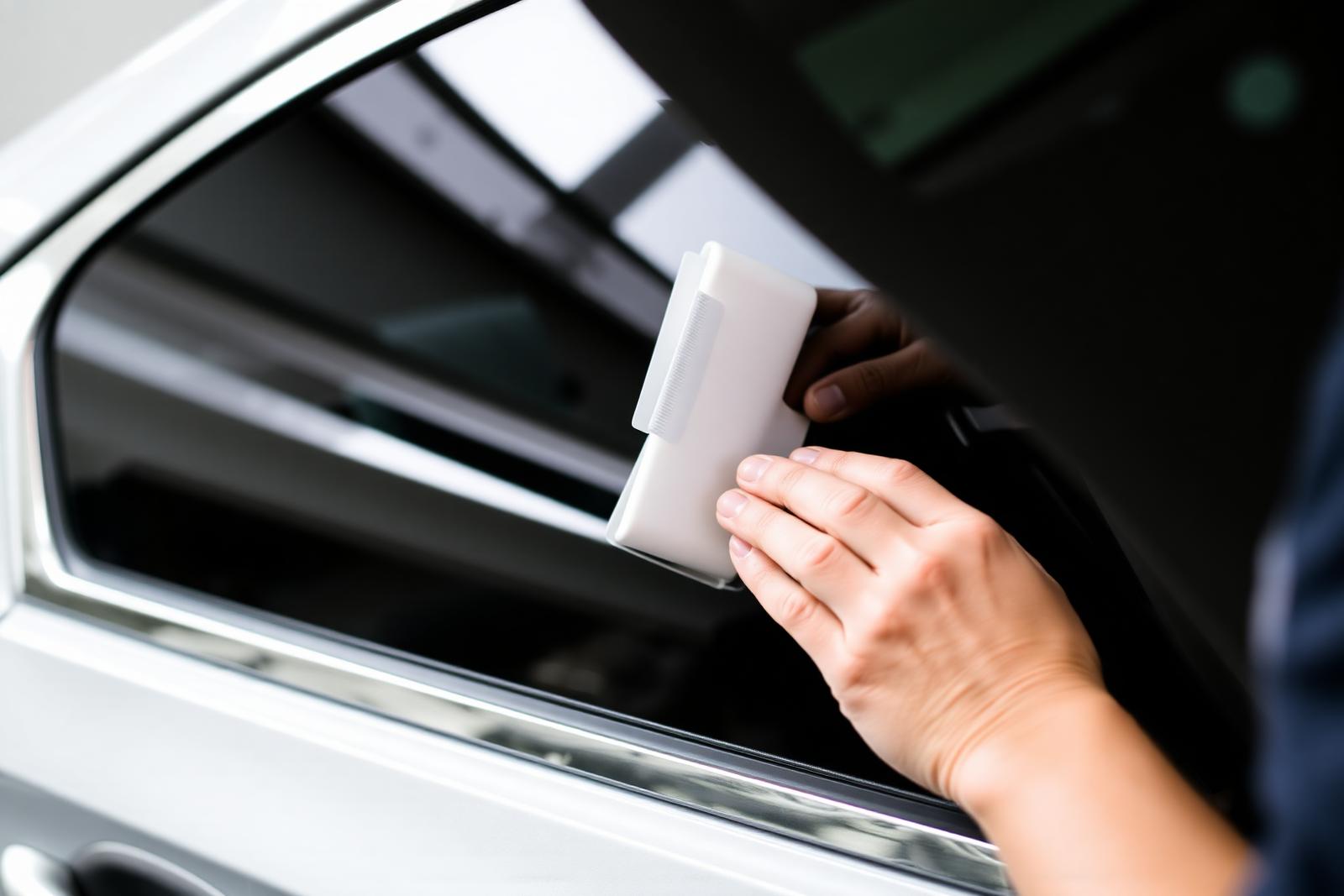 Professional installer applying ceramic window tint film with a squeegee
